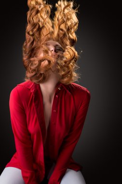 Seksi model kırmızı kıvırcık saçları sallayarak poz