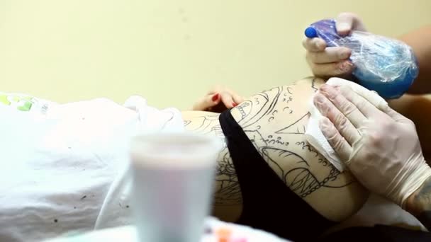 Татуювання художник протирає надлишок чорнила з тіла дівчаток — стокове відео