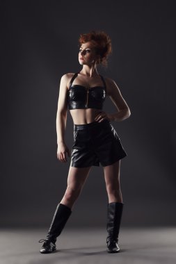 Kendine güvenen Kızıl saçlı deri kostüm dansçı