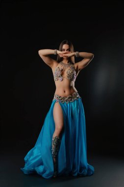 Bir kadın karanlık bir bölgede yılanla dans ediyor. Yılanı tutarken zarifçe hareket ediyor. Ayarlar onun hareketlerini vurguluyor ve dansa odaklanmasını sağlıyor..