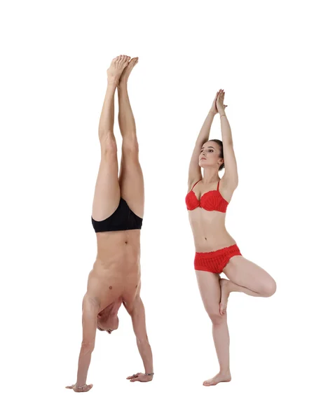 Man doing handstand and woman stand on one leg — Stock Photo, Image
