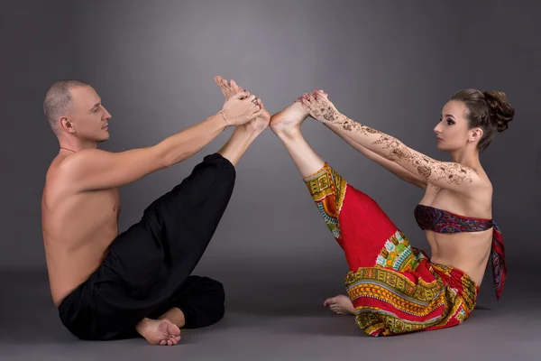 Cvičení jógy v páru. Obraz na šedém pozadí — Stock fotografie