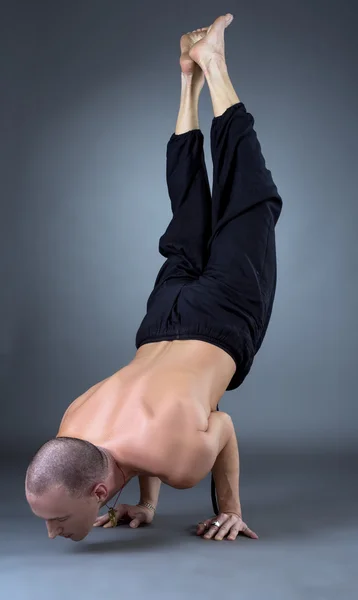 Yogui haciendo handstand en estudio, sobre fondo gris — Foto de Stock