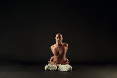 Gri zemin üzerine lotus poz orta yaşlı yogi