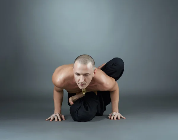 Jogín provádí asana. Studio záběr na šedé pozadí — Stock fotografie