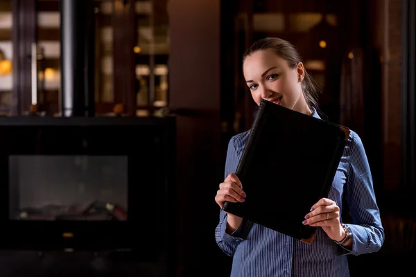 Усміхнена офіціантка ховає обличчя за меню — стокове фото