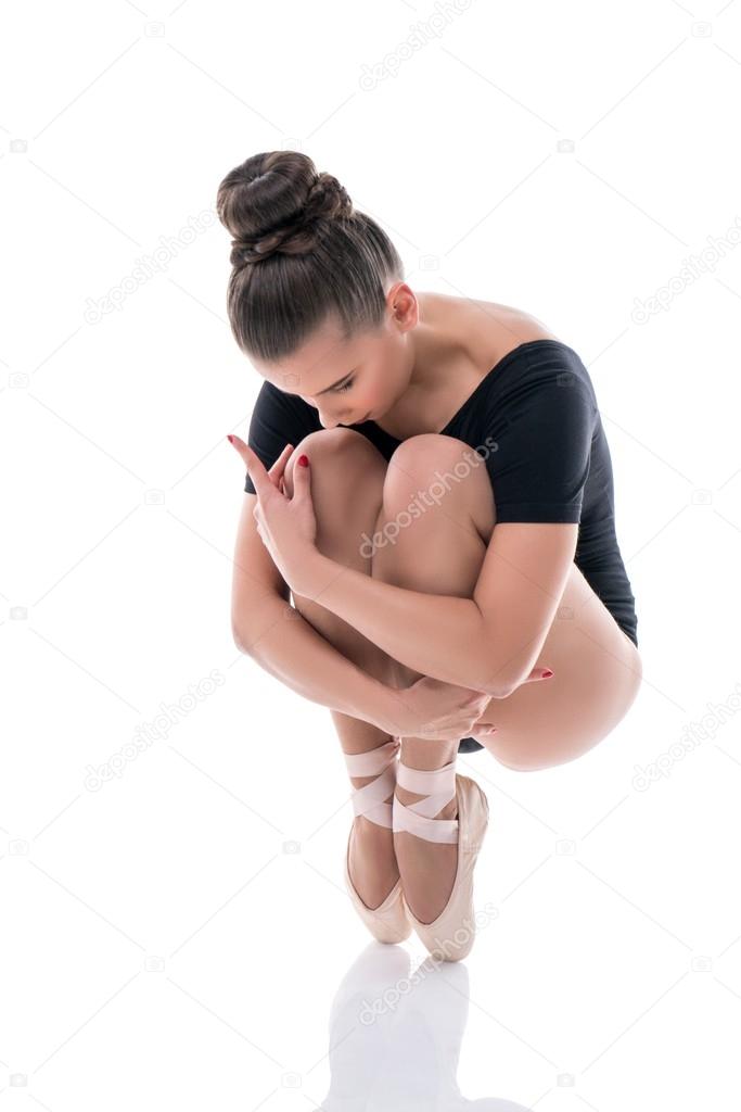 Ballerina on pointes, clutching her knees to chest
