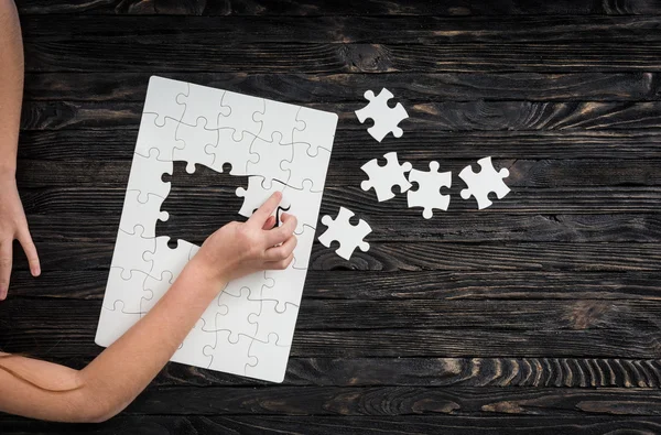 Hands starting to collect puzzle pieces — Stock Photo, Image