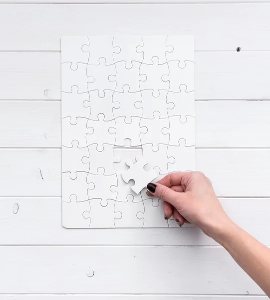 Hand holding a piece of white uncompleted puzzle — Stock Photo, Image