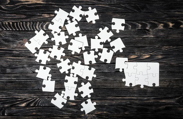 White puzzle pieces on dark table — Stock Photo, Image