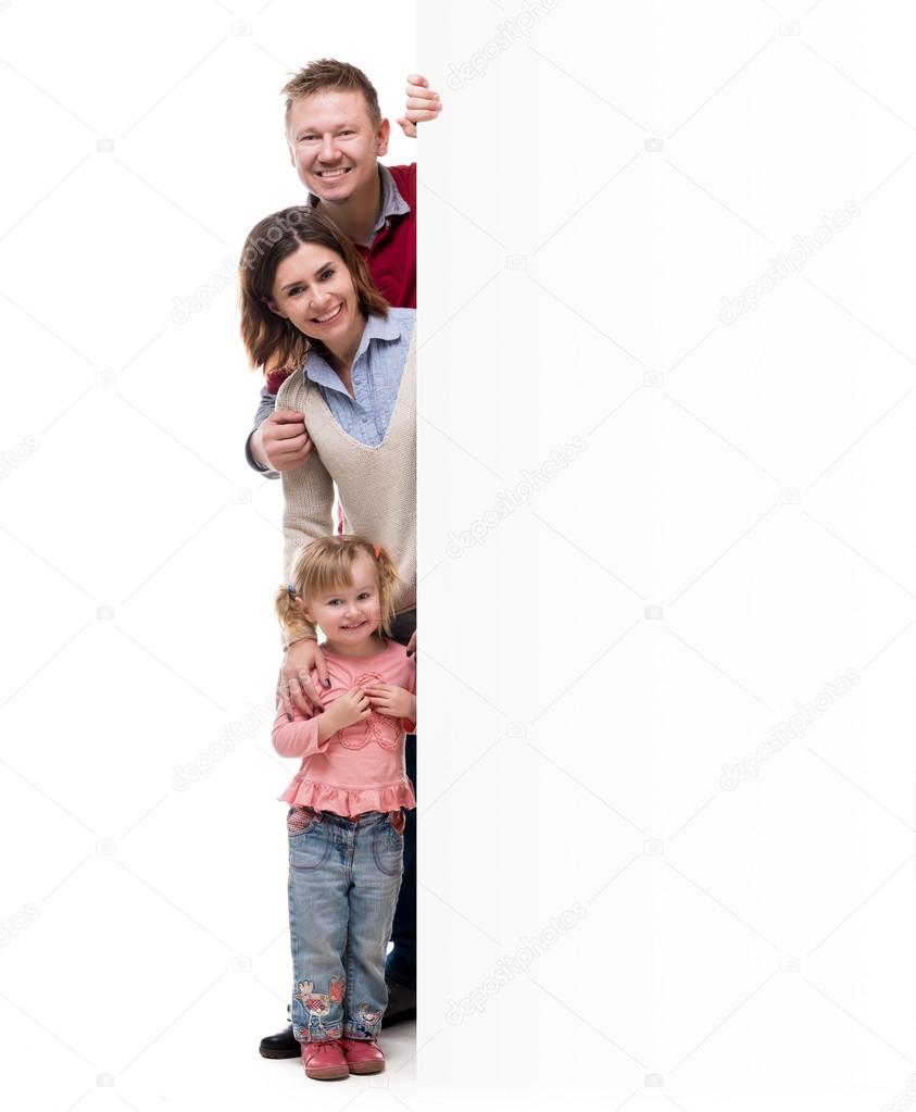 father, mother and little daughter peek out from behind empty blank