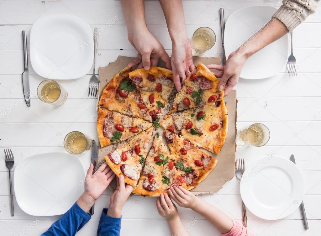 four hands taking pieces of pizza