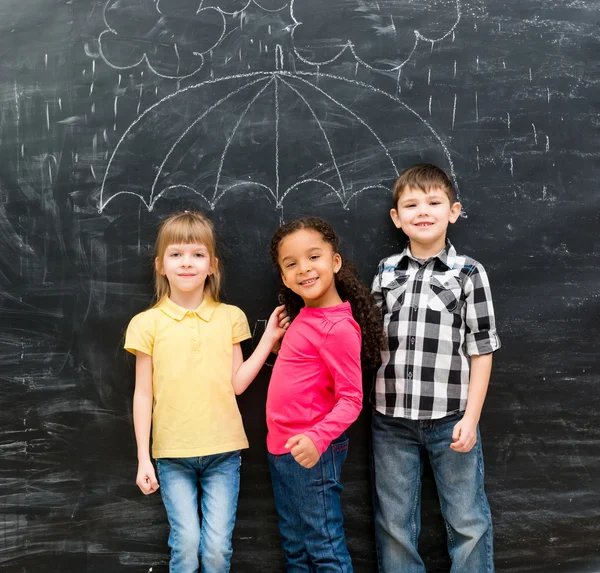 ब्लैकबोर्ड पर चित्रित छाता के साथ तीन मजेदार बच्चे — स्टॉक फ़ोटो, इमेज