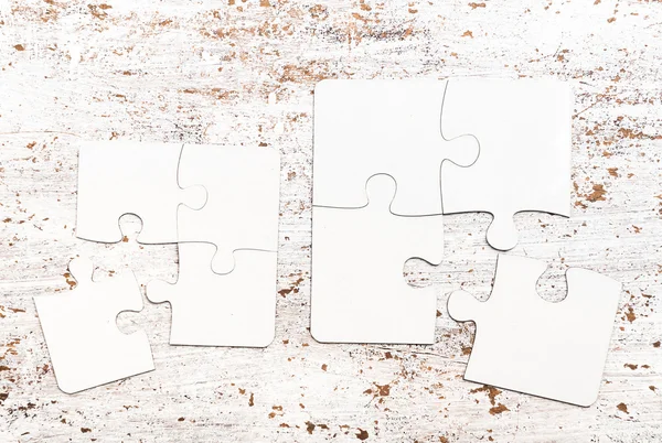 Peças de tamanho diferente de quebra-cabeça branco em uma mesa — Fotografia de Stock