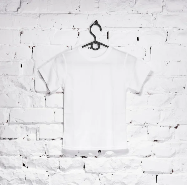 Цегляна побілена стіна з білою футболкою на вішалці — стокове фото