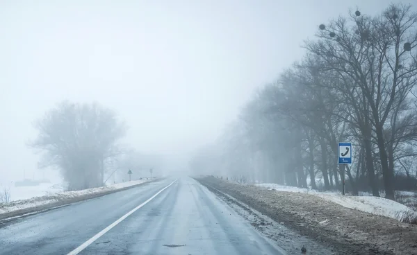 両側の汚れた雪と霧の道 — ストック写真