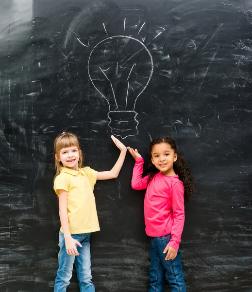 Two cute little girls showing drawn lamp with hands — Stock Photo, Image