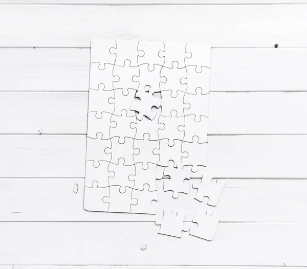 Puzzle blanc inachevé sur table blanche — Photo