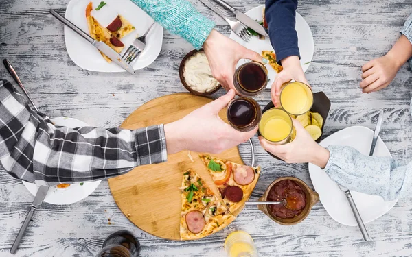 People clanging glasses together having pizza — Stock Photo, Image