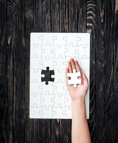 Hand with the last piece of white uncomleted puzzle — Stock Photo, Image