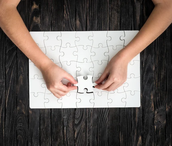 Hands completing wthite puzzle with the last piece — Stock Photo, Image