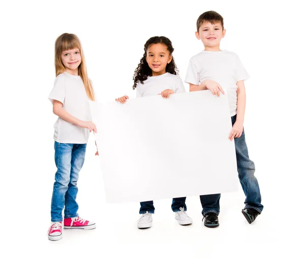 Tres niños de tez diferente con una hoja de papel vacía — Foto de Stock