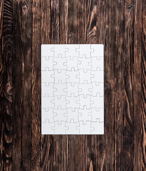 Completed white puzzle on wooden background — Stock Photo, Image