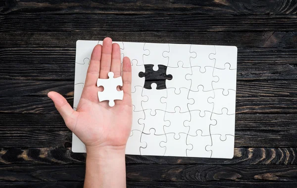 Hand with the last piece of white uncomleted puzzle — Stock Photo, Image