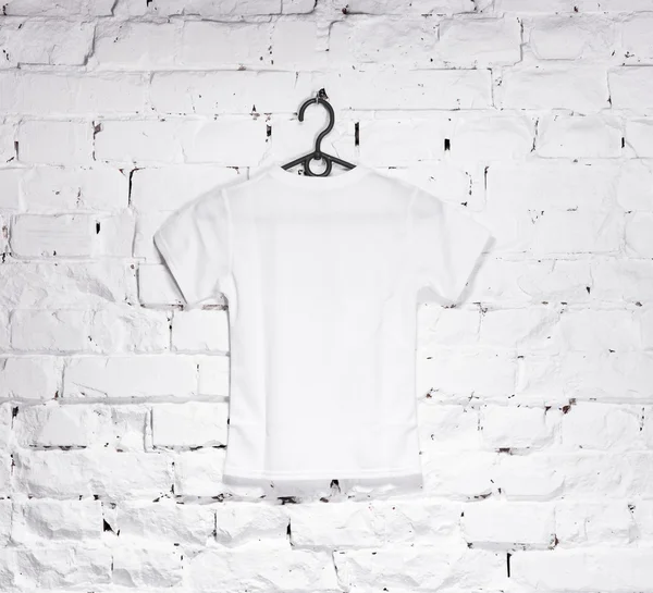 Цегляна побілена стіна з білою футболкою на вішалці — стокове фото