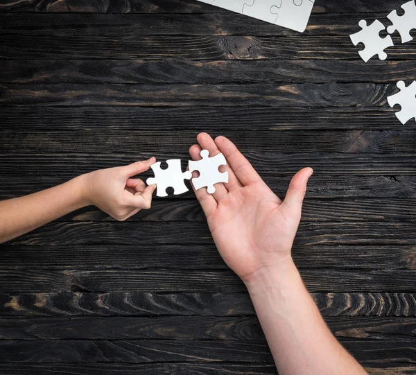 Pieces of white puzzle in hands — Stock Photo, Image