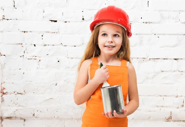 Милая маленькая девочка в оранжевой форме с оловом в руках — стоковое фото