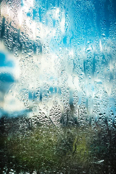 Céu azul nublado através de vidro molhado — Fotografia de Stock