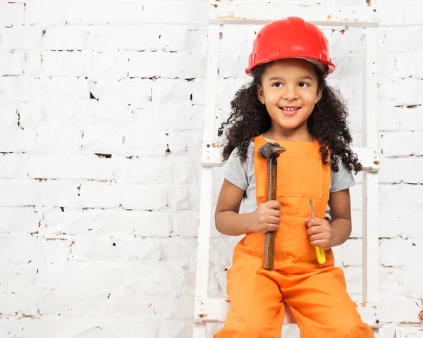 Little girl in helmet with hammer and screwdriver — Stock Photo, Image