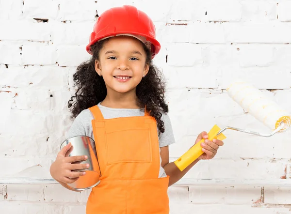 Liten flicka-arbetare med färg och roller i händerna — Stockfoto