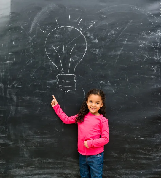 Smiling little girl pointing at drawn on the blackboard lamp — Stock Photo, Image