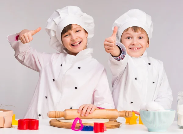 Двое улыбающихся детей на кухне с поднятыми вверх большими пальцами — стоковое фото