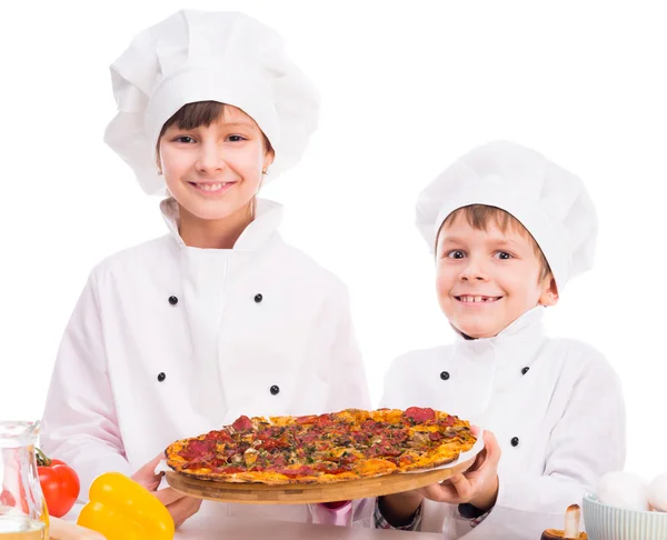 Dos pequeños cocineros porcionando pizza cocida — Foto de Stock