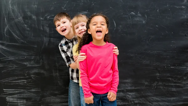 Tre olika barn står en genom en kikar ut från bakom varandra — Stockfoto