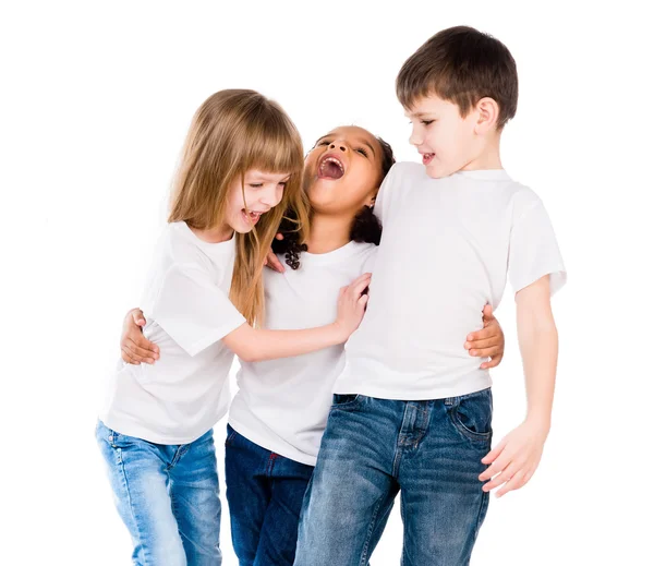 Tres niños de moda con diferente tez se ríen y se abrazan —  Fotos de Stock