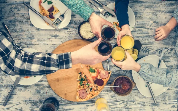 People clanging glasses together having pizza — Stock Photo, Image