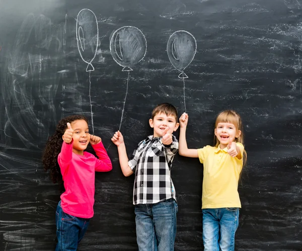 Három mosolygó gyermek tartása imaginaru remek készült léggömbök — Stock Fotó