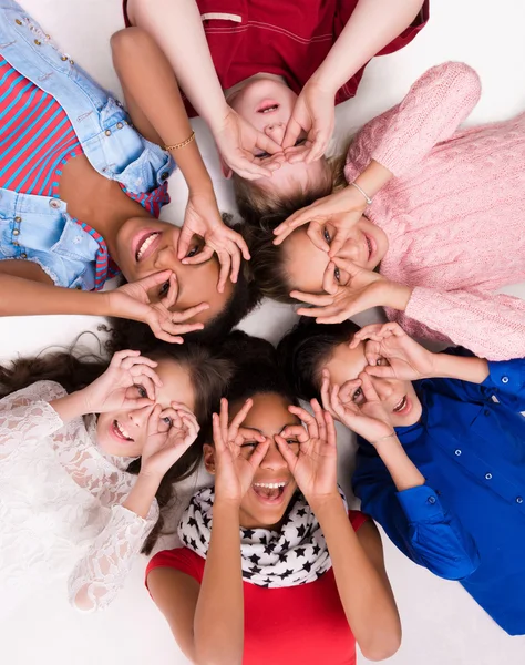 Niños acostados en el suelo cabeza a cabeza con gafas de los dedos —  Fotos de Stock