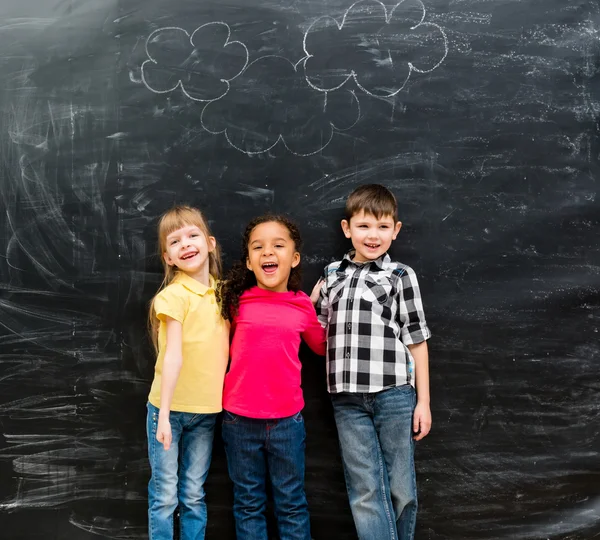 Trois enfants riants différents avec tableau noir sur fond — Photo