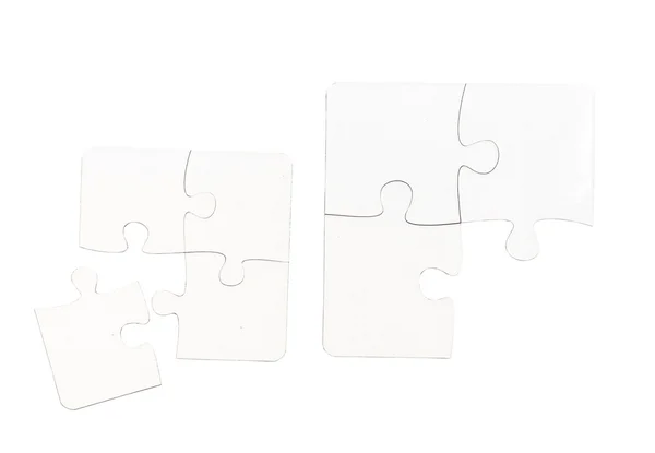 Forskellige størrelse stykker af hvide puslespil på et bord - Stock-foto