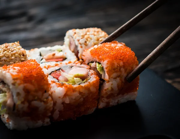 Close-up de rolos de sushi com pauzinhos — Fotografia de Stock