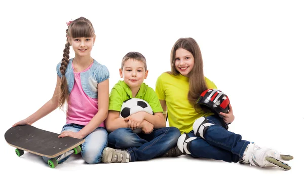 Tre söta barn sitter på golvet med sportutrustning — Stockfoto