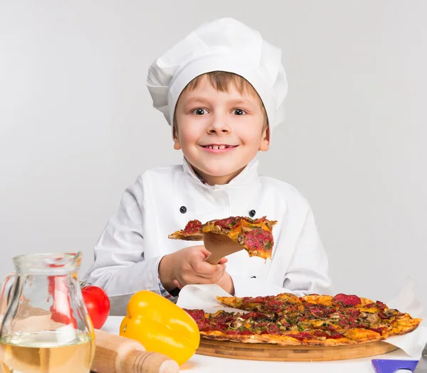 Grappige kleine jongen houdt een stuk van smakelijke pizza — Stockfoto