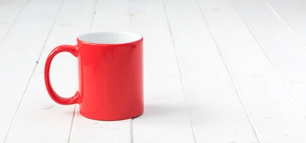 Taza roja con el interior blanco en la mesa — Foto de Stock