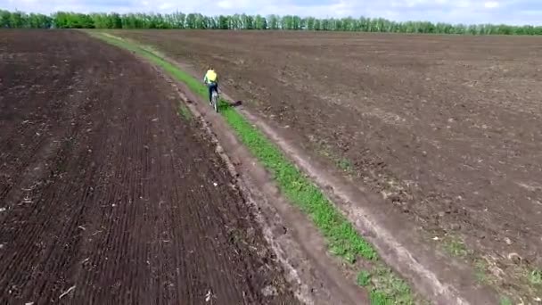 Bycyclist ridning cykeln i ett fält — Stockvideo