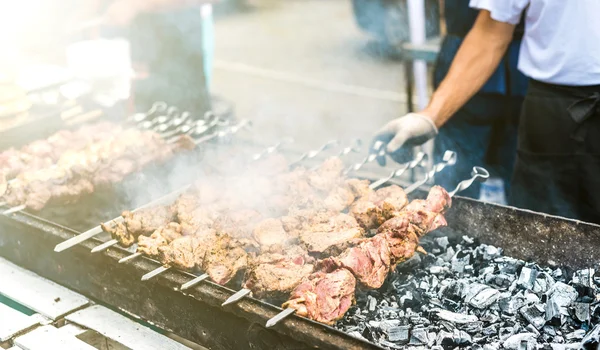 Hand turning the skewers with kebab on mangal — Stock Photo, Image